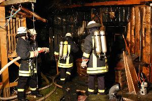 Bild: Unter dem Einsatz von Atemschutzger&amp;auml;ten durchsuchten die Feuerwehrleute das Gartenhaus nach weiteren Brandnestern