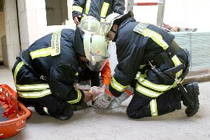 Bild: Versorgung eines verletzten Arbeiters: Rettungssanit&amp;auml;ter der Feuerwehr legen dem Verunfallten eine Halskrause zum Stabilisieren der Wirbels&amp;auml;ule an