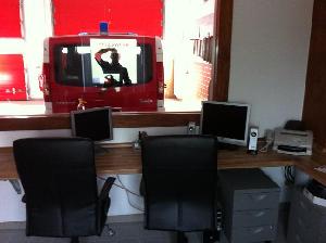 Bild: Funkraum mit gro&amp;szlig;z&amp;uuml;gigem Arbeitsbereich und gro&amp;szlig;em Sichtfenster zur Fahrzeughalle